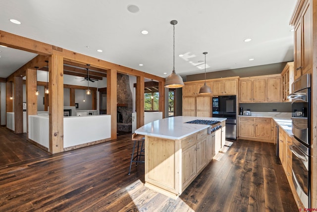 kitchen featuring light brown cabinetry, ceiling fan, stainless steel gas stovetop, a kitchen island, and dark wood-style floors