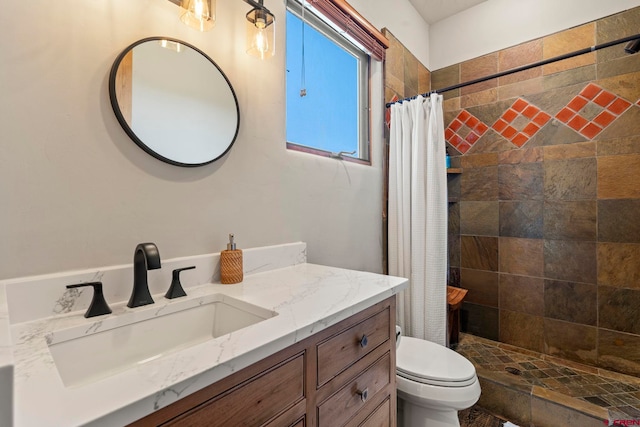 full bathroom with vanity, a tile shower, and toilet