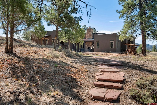 rear view of property with a chimney and stucco siding