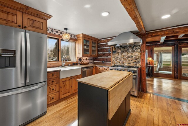 kitchen featuring wooden counters, appliances with stainless steel finishes, light wood-type flooring, a sink, and ventilation hood