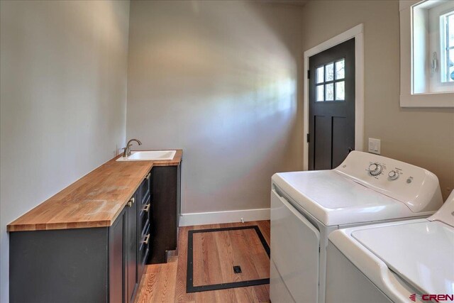 474 Lakewood St, Pagosa Springs, CO 81147 - laundry area featuring cabinet space, a sink, baseboards, light wood-style floors, and washer and clothes dryer