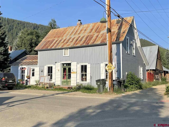 view of front facade with a standing seam roof, a chimney, and metal roof