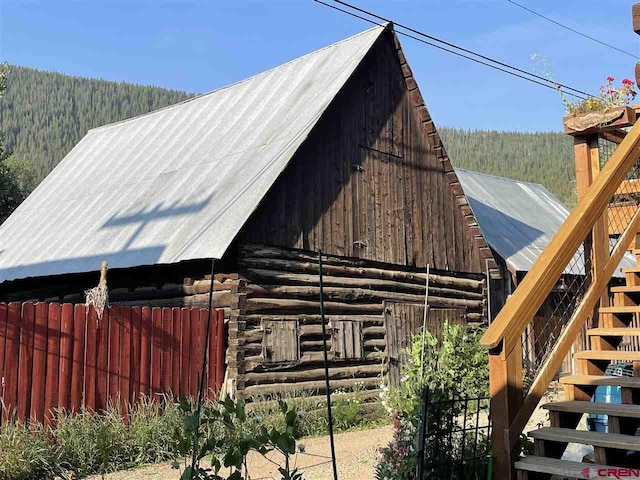 exterior space featuring a barn, log exterior, metal roof, and a wooded view