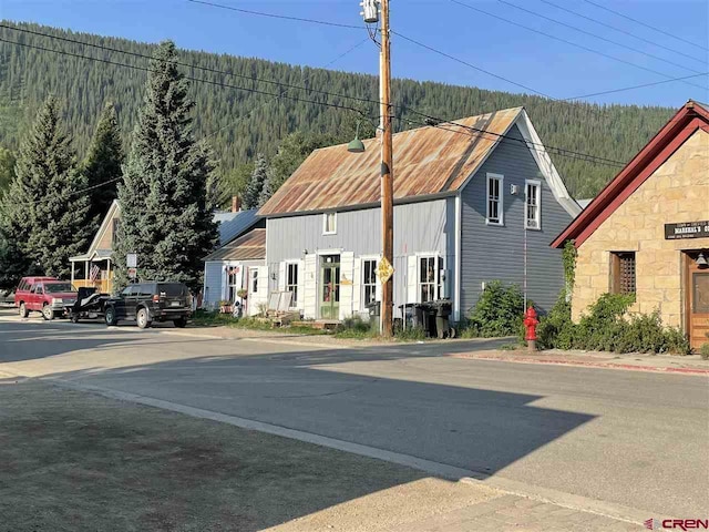 view of front facade featuring a view of trees and stone siding