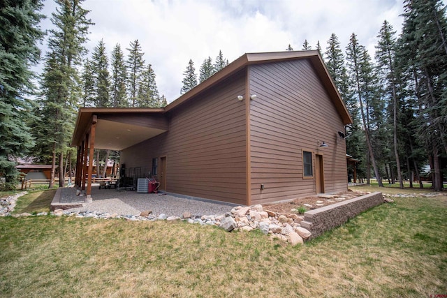 view of side of property with a lawn, central AC, and a patio area