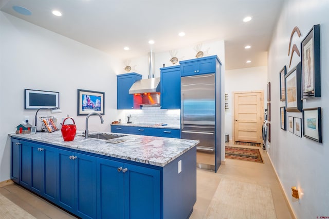 kitchen featuring backsplash, blue cabinets, a sink, built in refrigerator, and a peninsula