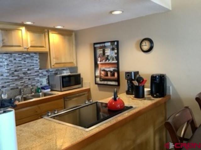 kitchen featuring light countertops, a sink, backsplash, and stainless steel appliances