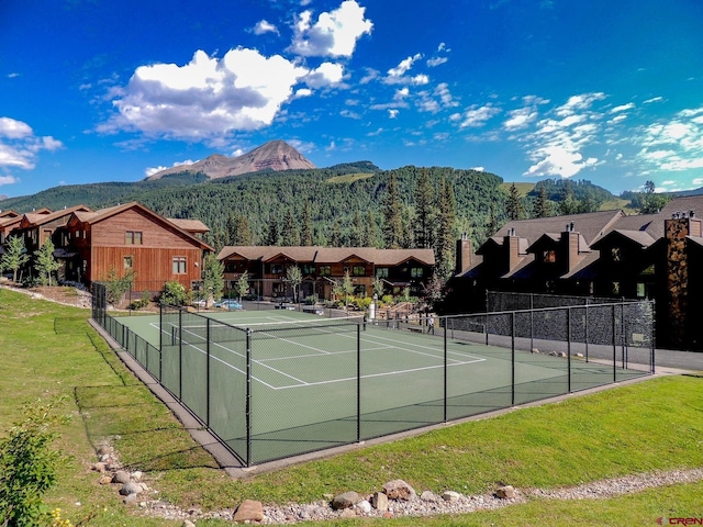 view of tennis court with fence and a residential view