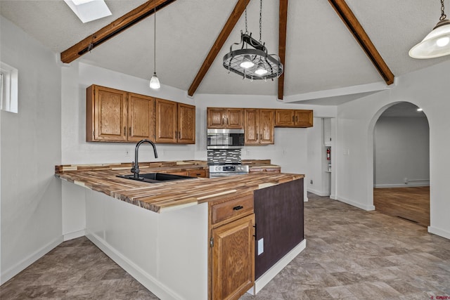 319 Rosevale Rd, Grand Junction, CO 81507 - kitchen with appliances with stainless steel finishes, a sink, arched walkways, butcher block countertops, and brown cabinetry