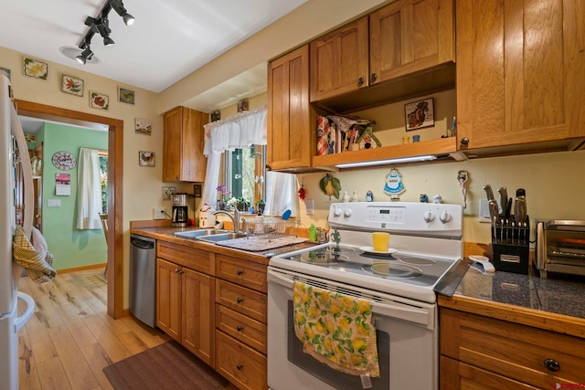 kitchen with brown cabinetry, track lighting, white appliances, tile countertops, and light wood-style flooring