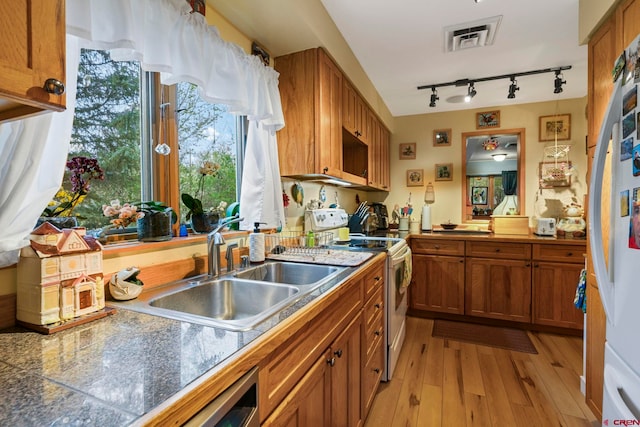 kitchen featuring visible vents, light wood-style flooring, brown cabinets, and white range with electric cooktop