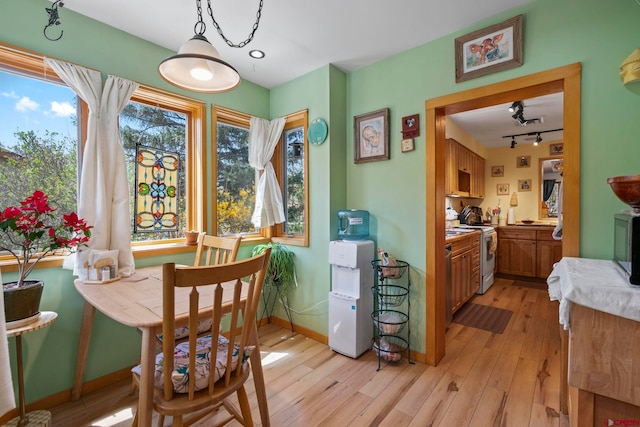 dining area with baseboards, rail lighting, and light wood-style flooring