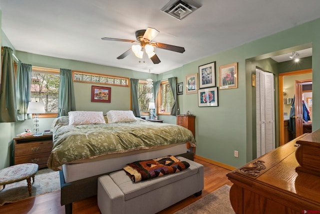 bedroom featuring baseboards, a ceiling fan, wood finished floors, and visible vents