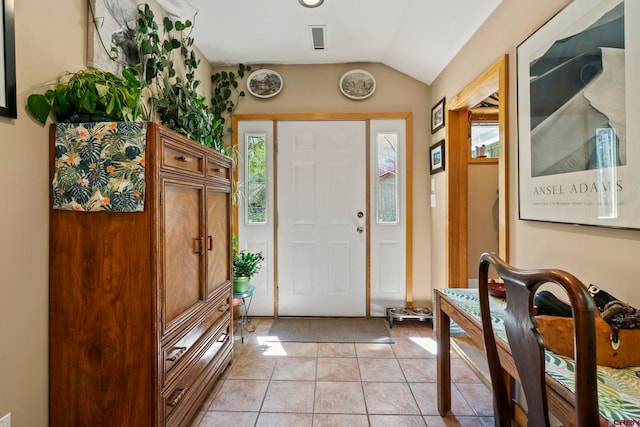 foyer featuring visible vents, plenty of natural light, light tile patterned flooring, and vaulted ceiling