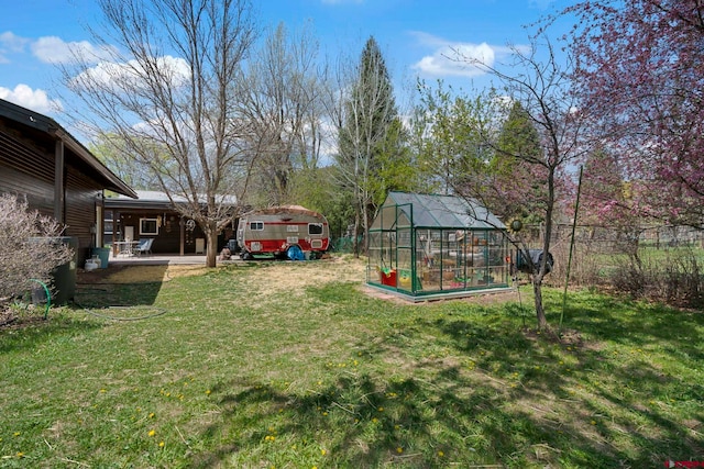 view of yard with a patio, an outbuilding, fence, and a greenhouse
