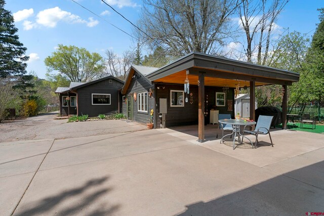 view of front of property featuring a storage unit, an outbuilding, and a patio