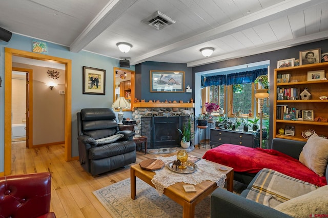 living room featuring beam ceiling, a fireplace, light wood-style floors, baseboards, and visible vents