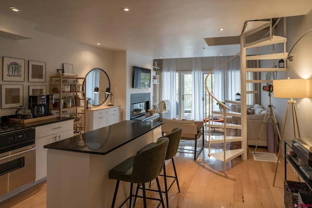 kitchen with dark countertops, a breakfast bar, range, light wood-style flooring, and white cabinetry
