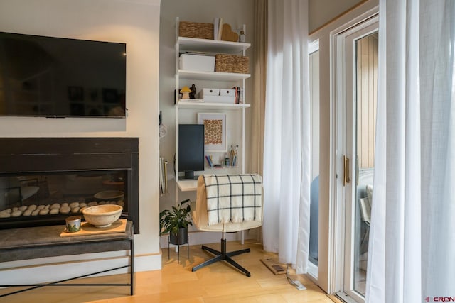sitting room featuring visible vents, a glass covered fireplace, and wood finished floors