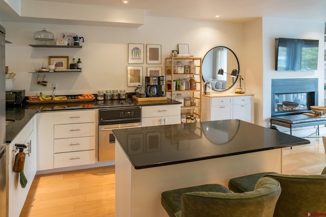 kitchen with white cabinets, recessed lighting, dark countertops, and stainless steel oven