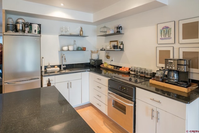 kitchen featuring white cabinets, open shelves, a sink, dark stone countertops, and stainless steel appliances