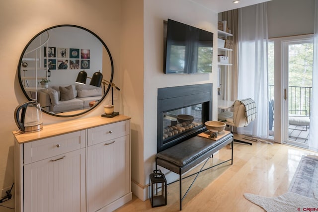 sitting room with light wood-style flooring and a glass covered fireplace