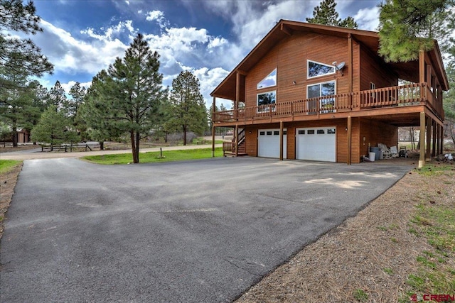 view of side of home featuring a deck, an attached garage, driveway, and stairs