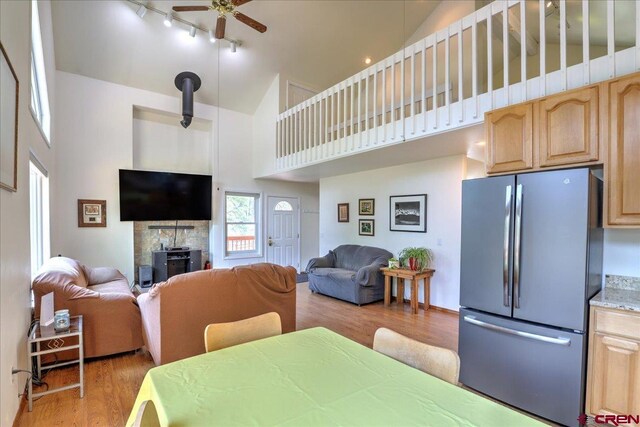 dining area featuring light wood-type flooring, a ceiling fan, track lighting, and high vaulted ceiling