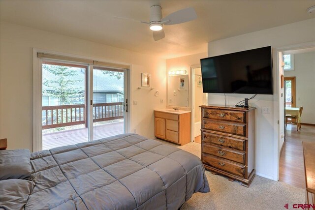 bedroom with a sink, access to exterior, light colored carpet, a ceiling fan, and ensuite bath