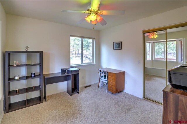 office area with a ceiling fan, baseboards, light carpet, and plenty of natural light