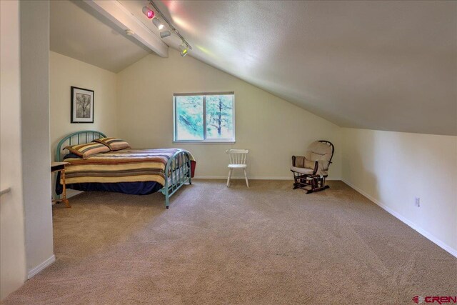 bedroom featuring baseboards, rail lighting, vaulted ceiling with beams, and carpet