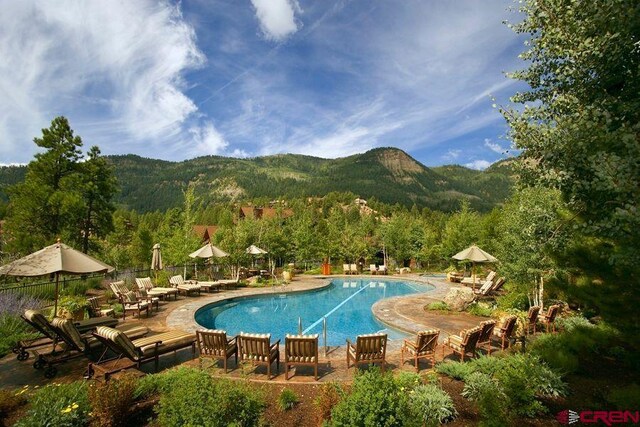community pool featuring fence, a mountain view, and a patio