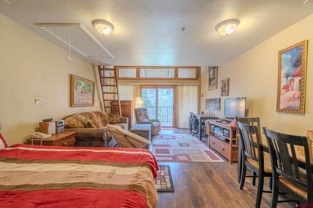 bedroom with access to outside, attic access, and wood finished floors