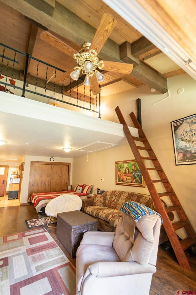 living area with ceiling fan, wood finished floors, stairway, and beamed ceiling