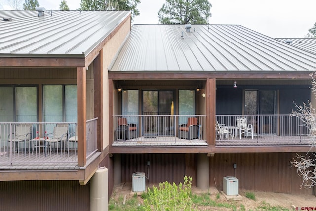 rear view of property featuring central air condition unit, a standing seam roof, and metal roof