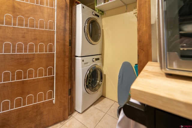 laundry area featuring stacked washing maching and dryer, tile patterned flooring, and laundry area