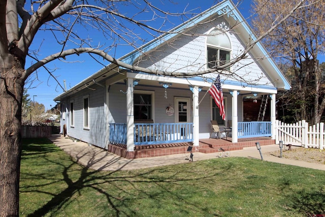 view of front facade featuring a front lawn, fence, and covered porch
