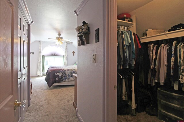 spacious closet with carpet floors, ceiling fan, and vaulted ceiling