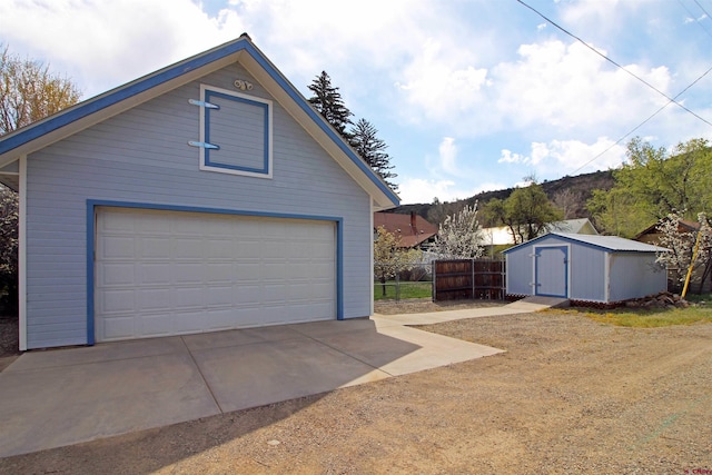 detached garage featuring a storage shed and fence