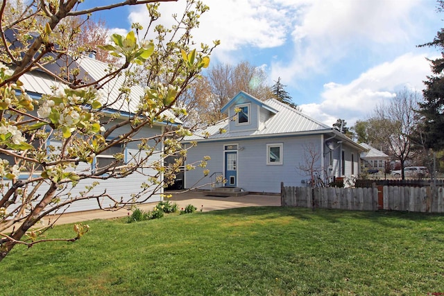 back of house featuring a lawn, a patio area, fence, and metal roof