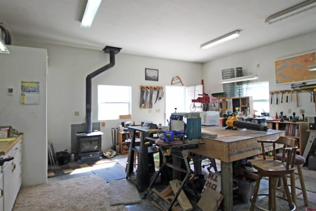 dining room with a workshop area, carpet, and a wood stove