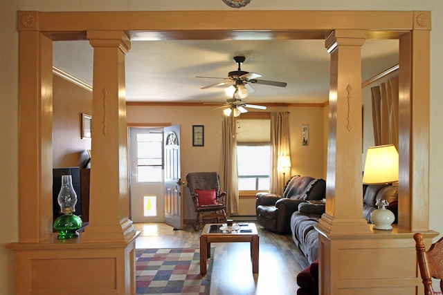 living area with a ceiling fan, decorative columns, and a healthy amount of sunlight