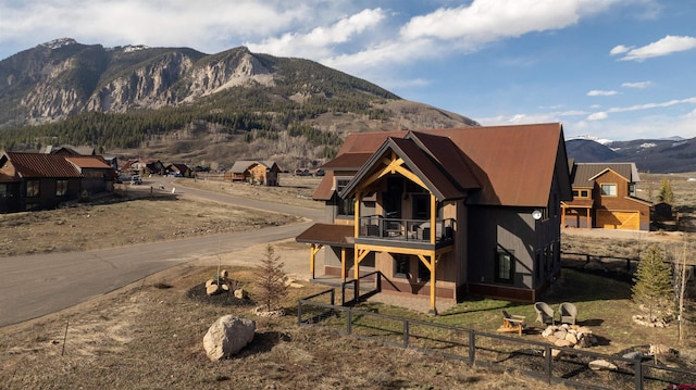 rear view of house with fence, a mountain view, and a balcony