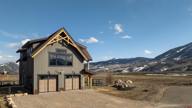 exterior space featuring a garage, fence, a mountain view, and driveway