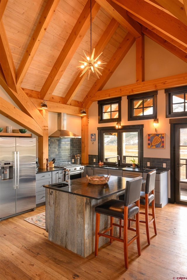 96 Chestnut Ln, Crested Butte, CO 81224 - kitchen with beam ceiling, dark countertops, high vaulted ceiling, wall chimney range hood, and stainless steel fridge