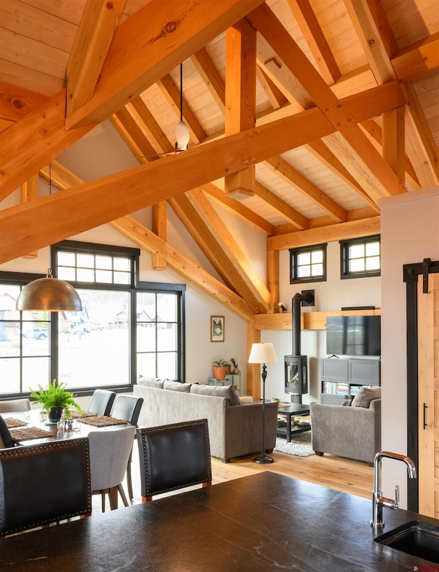 interior space featuring a wood stove, high vaulted ceiling, wooden ceiling, wood finished floors, and beamed ceiling