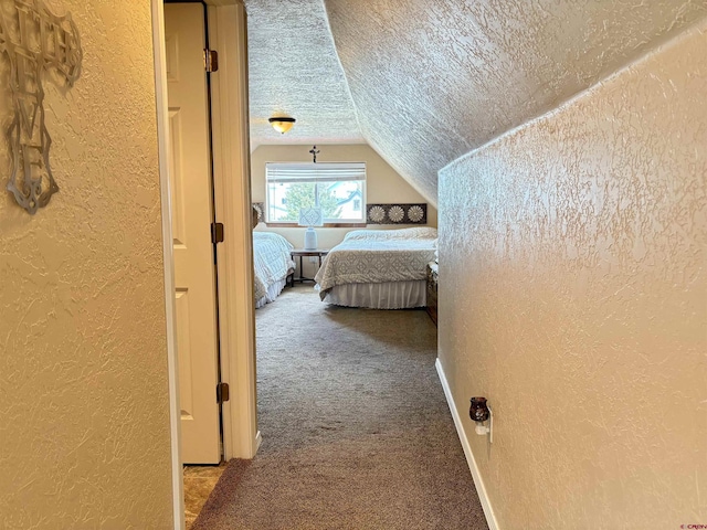 carpeted bedroom featuring a textured ceiling, a textured wall, and vaulted ceiling