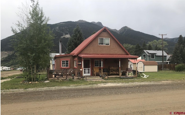 view of front of house with a storage unit, a mountain view, an outbuilding, and covered porch