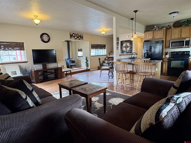 living area featuring a textured ceiling, light wood finished floors, and a wood stove