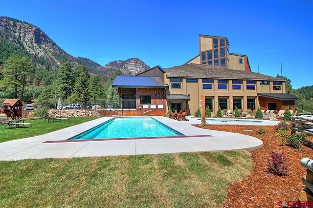 outdoor pool featuring a lawn, a mountain view, and a patio area